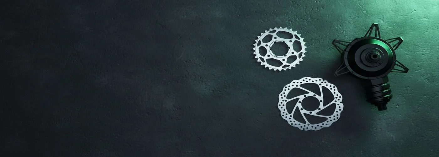 A hub motor, chainring and disc rotor on dark textured concrete.